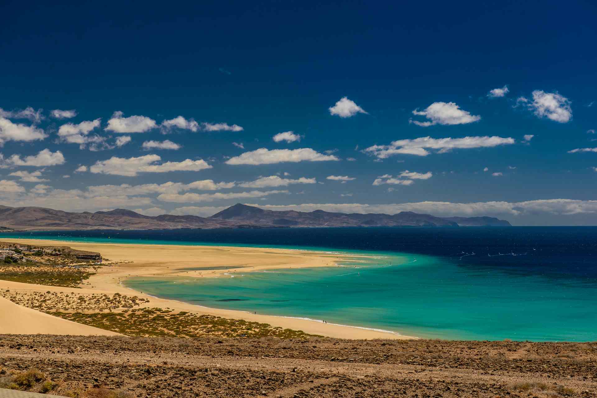 Weite Lagunenlandschaft mit hellen Sandbänken und türkisfarbenem Wasser vor Bergen